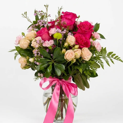 Hot pink garden roses and peach spray roses in a clear glass vase with pink ribbon — Blushing Peony Vase by Florent Floral Newmarket